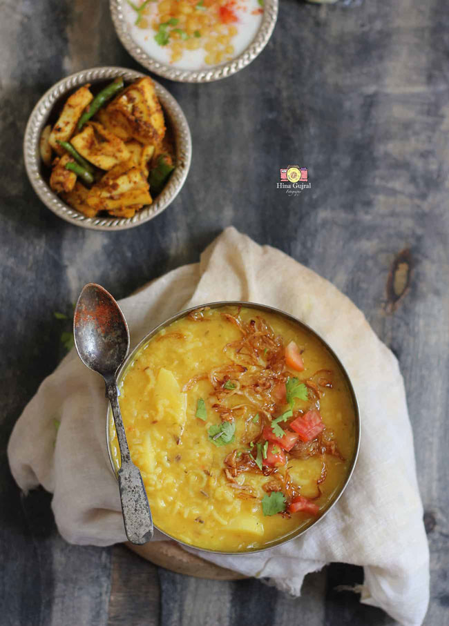 aerial shot of khichdi in a bowl with pickle and raita