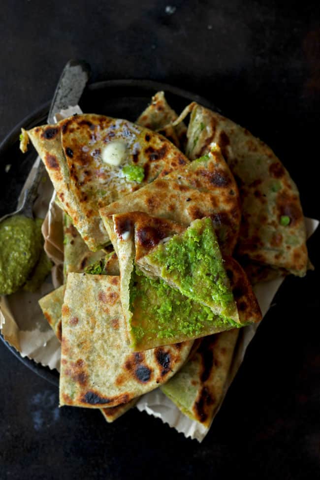 aerial shot of green pea paratha stacked on a black plate