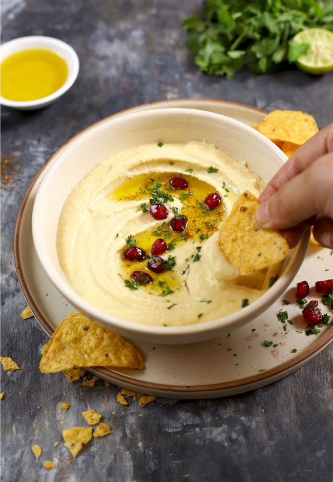 side shot of hummus in a bowl with the chips