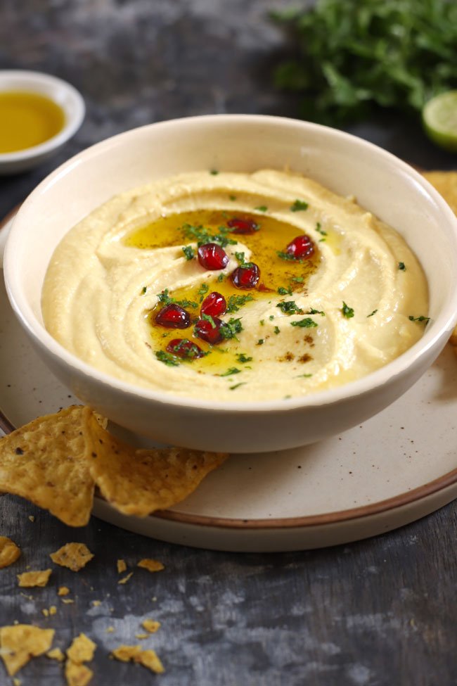 side close up shot of hummus in a white ceramic bowl