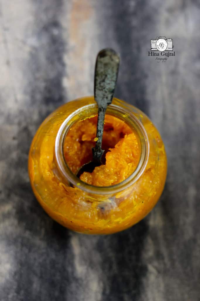 Aerial shot of aam chundo in a glass bottle with spoon.