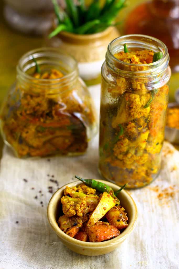 side shot of Punjabi mixed vegetable pickle in a ceramic bowl and glass jars