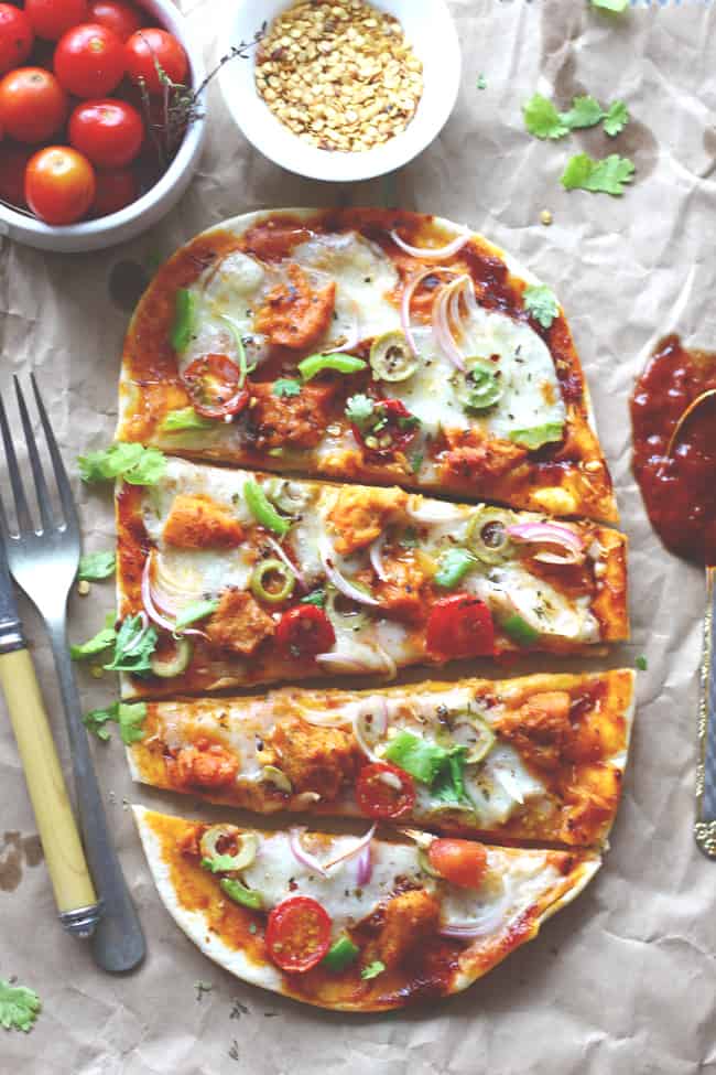 aerial shot of naan pizza cut into slices on a brown parchment paper