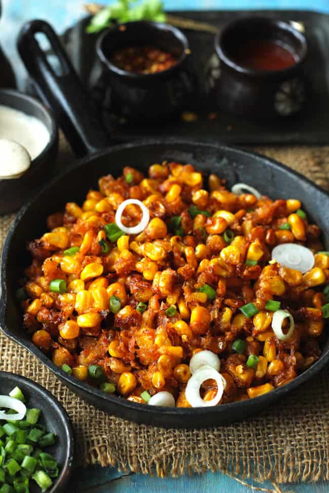 side close up shot of crispy corn stacked on a cast iron skillet