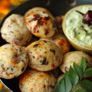 side shot of rava paniyaram in a cast iron kadhai