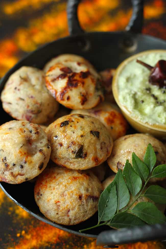 side shot of rava paniyaram in a cast iron kadhai