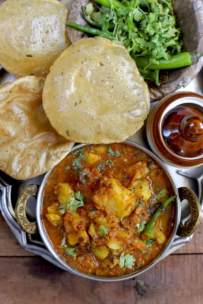 aerial shot of aloo ki sabzi with poori on a platter