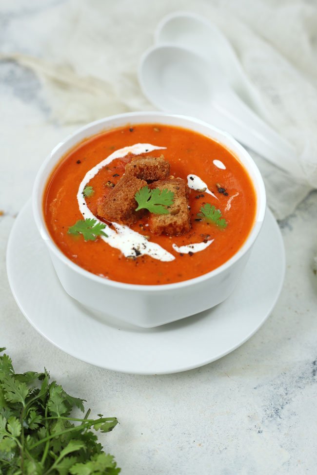 side close up shot of tomato soup in a white serving bowl