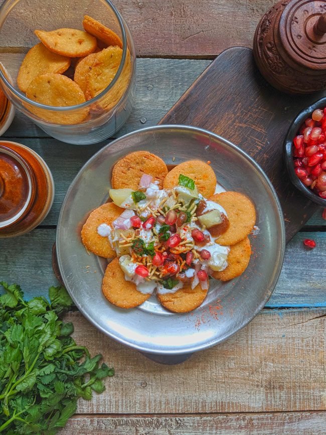 Papdi is the savory Indian crackers usually served with flavorful and colorful toppings of curd, chutney, and spices.