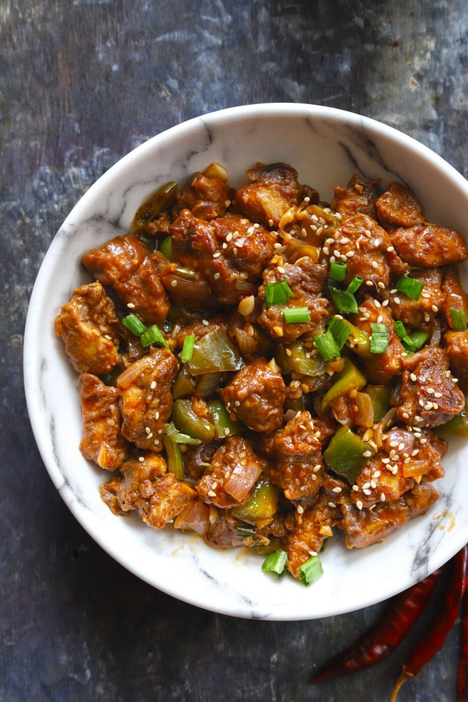 Aerial shot of chilli chicken in a white serving bowl.