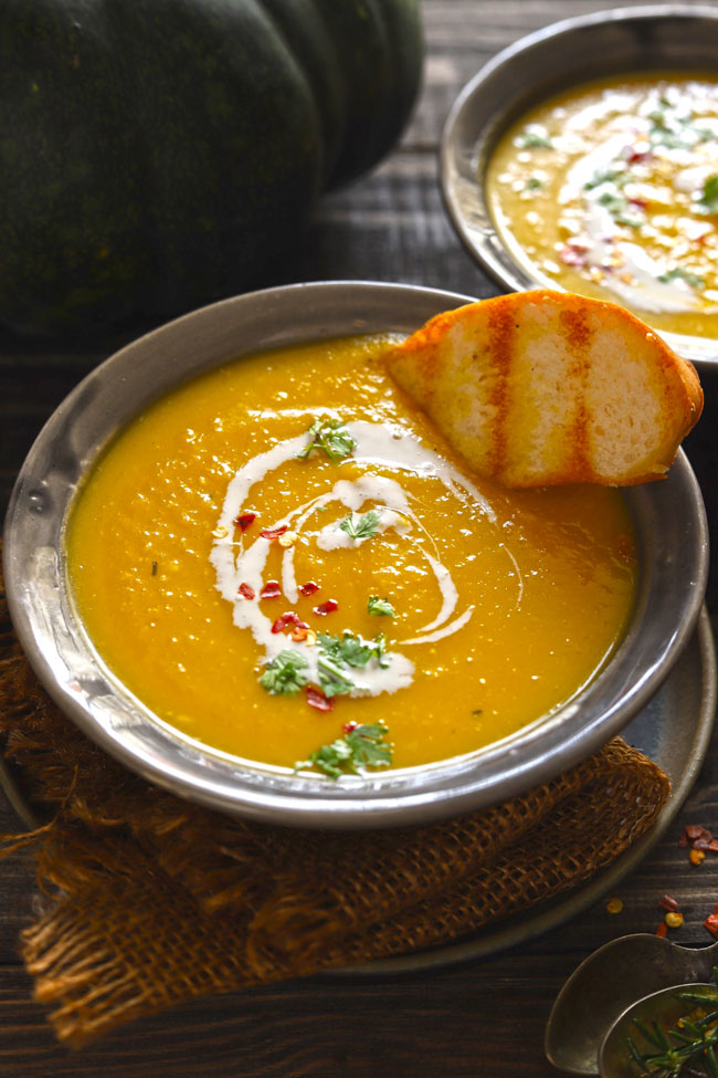 side close up shot of pumpkin soup in a grey ceramic bowl