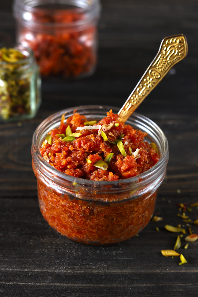 side shot of carrot halwa in a glass bowl with a golden spoon