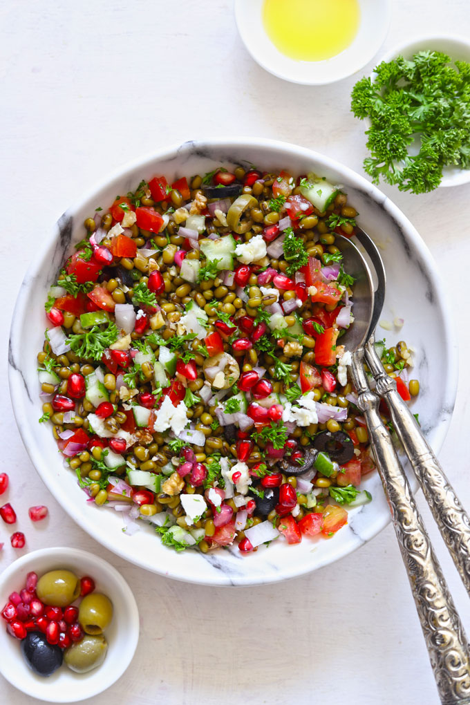 Lentil Salad in a white bowl with serving spoons on a white table