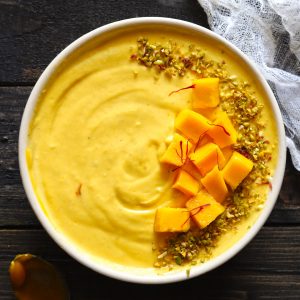 Aerial Shot of Mango Shrikhand Garnished With Chopped Mango Cubes, Saffron, and Pistachio