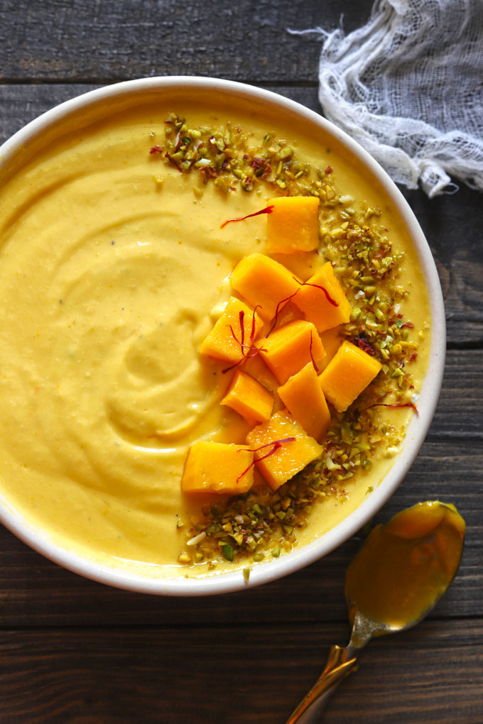 Aerial Shot of Mango Shrikhand Garnished With Chopped Mango Cubes, Saffron, and Pistachio