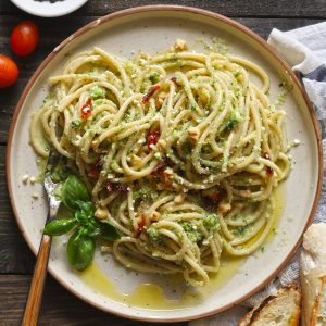 Aerial shot of broccoli pesto pasta in a cream color serving plate with fork.