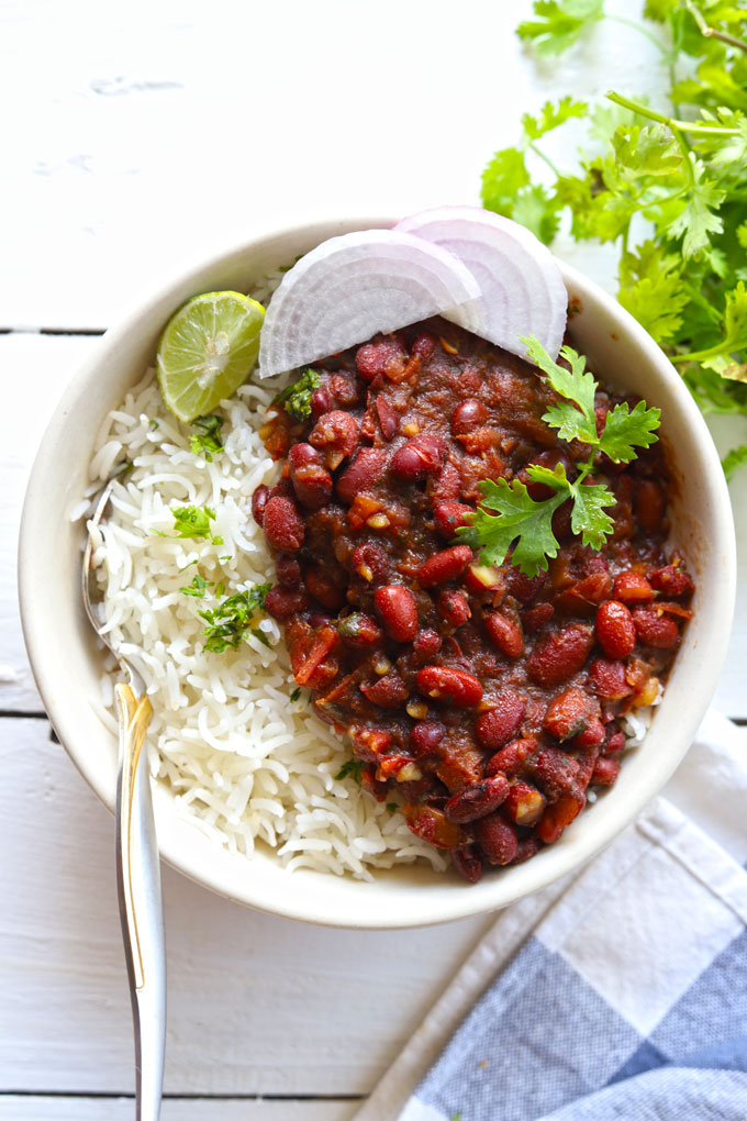 Aerial shot of rajma chawal in a white ceramic bowl with sliced onion and lemon wedges