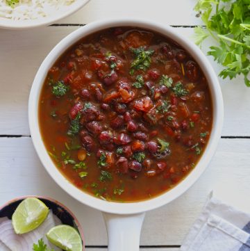 Aerial shot of rajma masala in a white serving bowl on a white background.