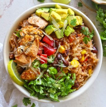 aerial shot of burrito bowl on white table with garnishes and cloth