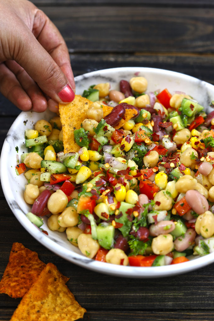 Close up shot of mixed beans salad with nachos on a white serving bowl.