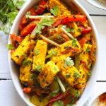 Aerial shot of paneer jalfrezi in an oval, white ceramic serving dish.