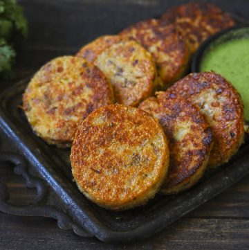 Suji Cutlet in a black tray with a green chutney.