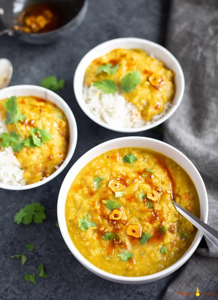 Red Lentil Curry with rice in serving bowls on a black surface