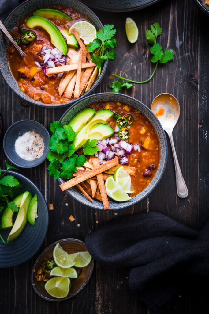 Red Lentil Tortilla Soup in a bowl on a black surface