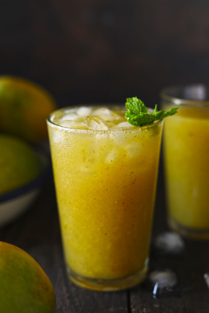 Side shot of aam ka panna in a glass garnished with mint leaves.