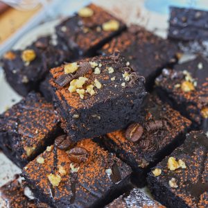 Side shot of stacked eggless brownies dusted with coffee powder.