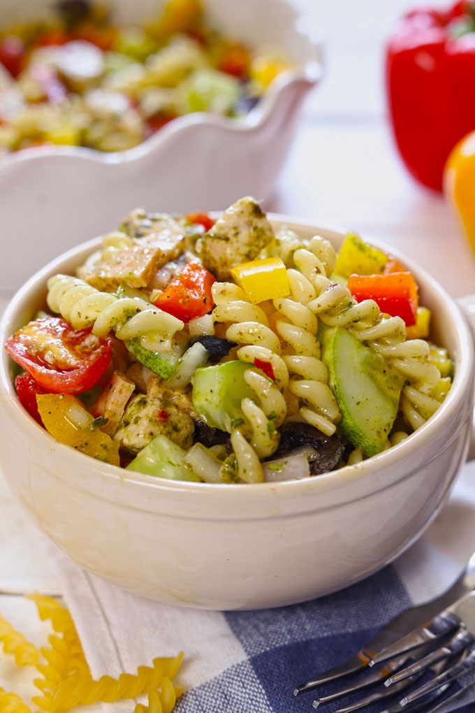 Side shot of pasta salad in a cream ceramic mug. 