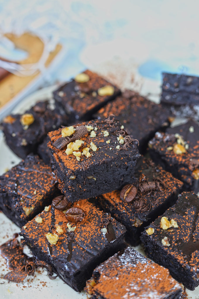 Side shot of stacked eggless brownies dusted with coffee powder.