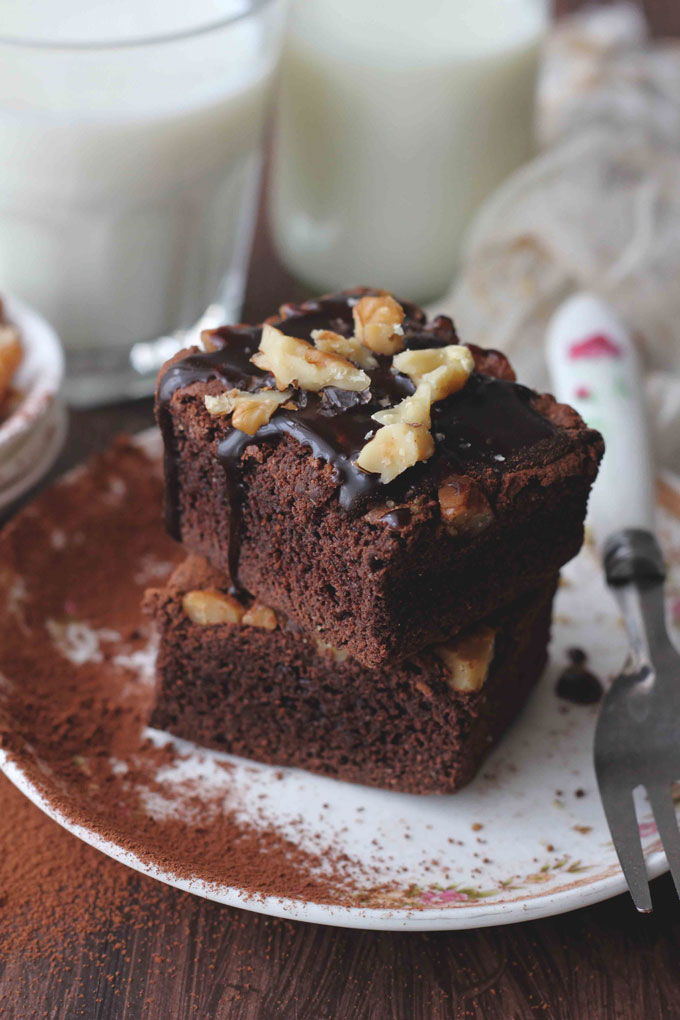 Side shot of stacked eggless brownies dusted with coffee powder.