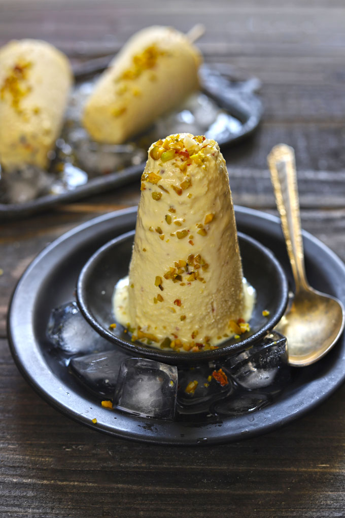 Side shot of kesar pista kulfi on a black round plate.