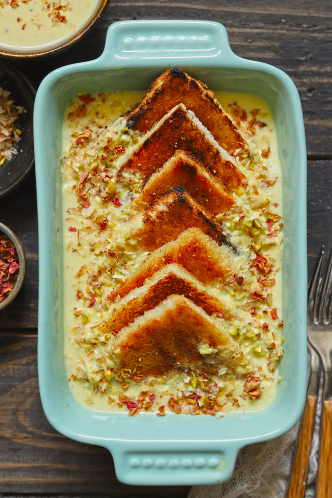 Aerial shot of baked shahi tukra in a green ceramic baking dish.