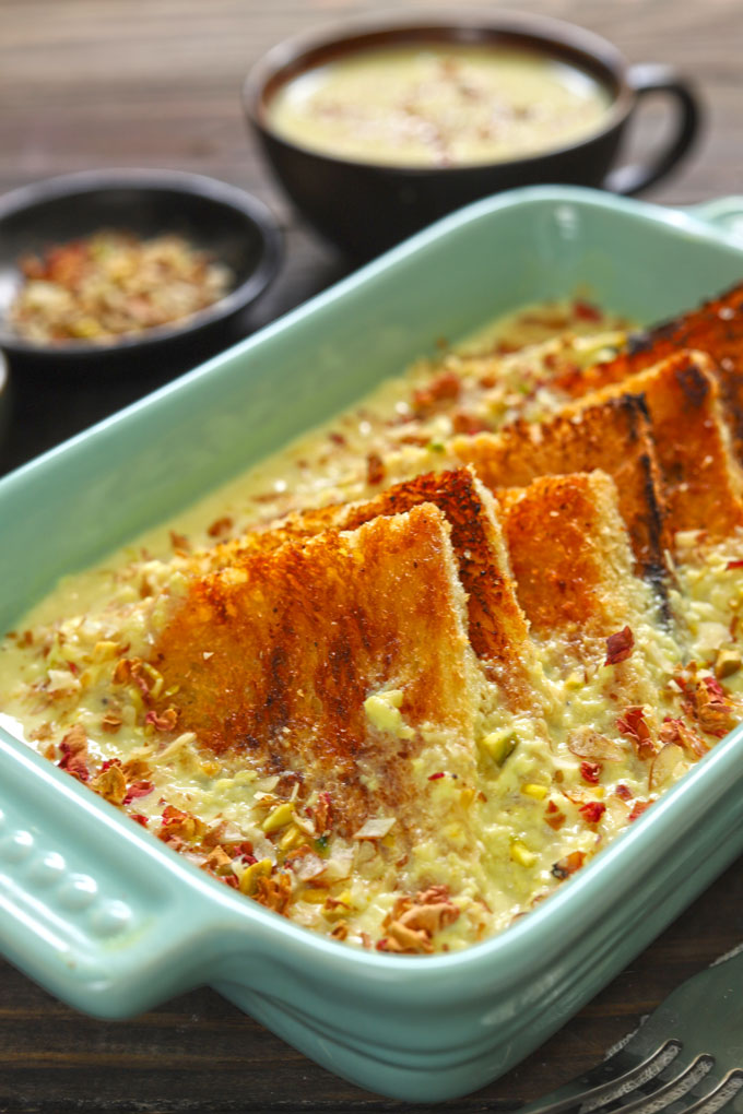 Side shot of baked shahi tukra in a green ceramic baking dish.