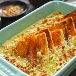 Side shot of baked shahi tukra in a green ceramic baking dish.