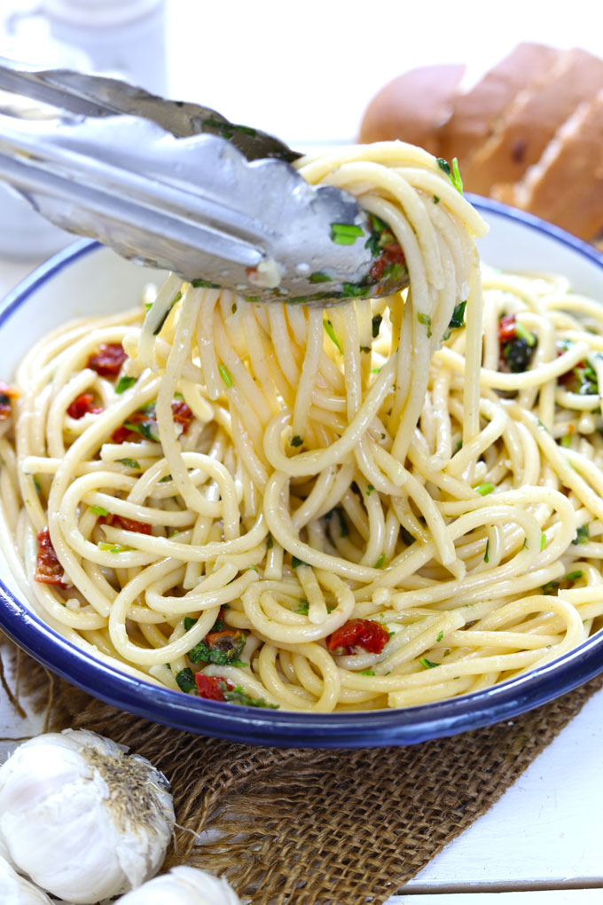 Side shot of tossing spaghetti in aglio e olio sauce. 