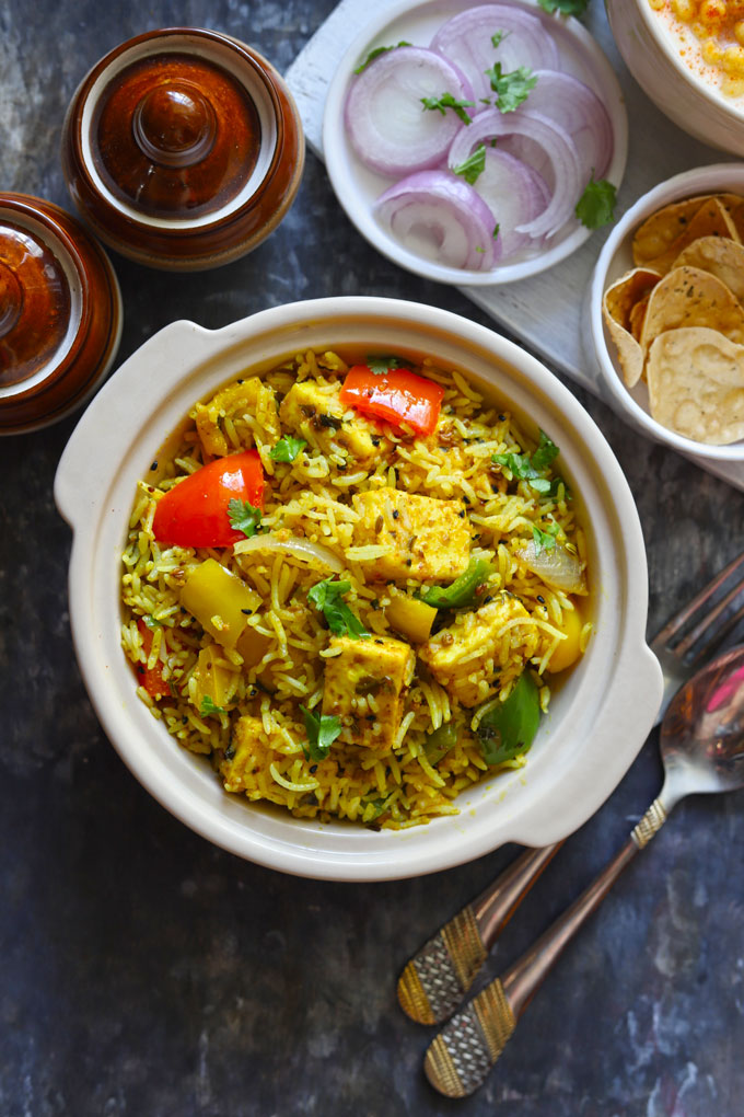 Aerial shot of achari paneer tikka pulao in a ceramic cream color serving bowl.