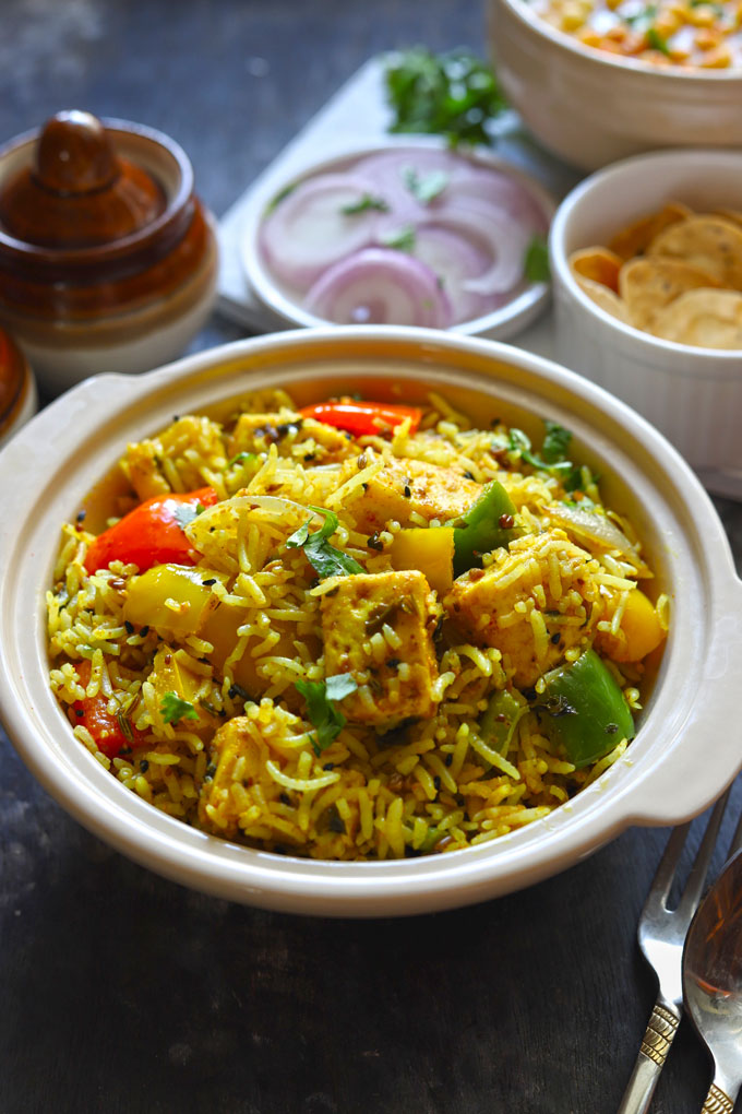 Side shot of paneer tikka pulao in a ceramic cream color serving bowl.