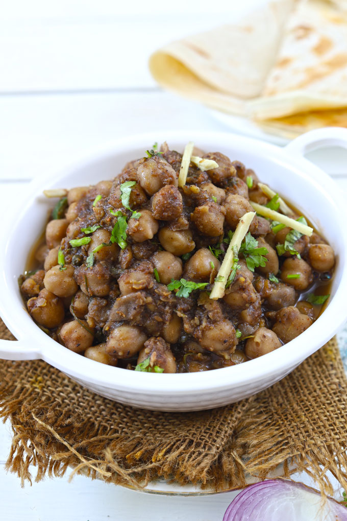 Side shot of chana masala in a white serving bowl