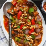 aerial shot of chilli mushroom in a white ceramic platter with a silver spoon