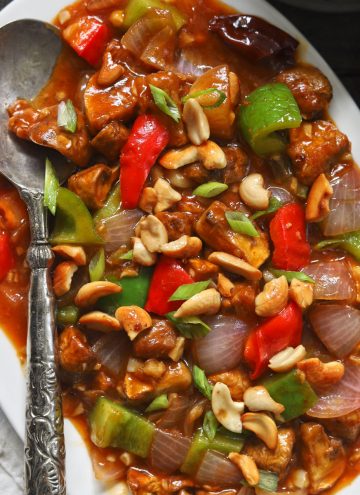 aerial shot of chilli mushroom in a white ceramic platter with a silver spoon