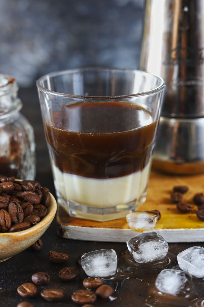 Side shot of condensed milk and brewed coffee in a glass.