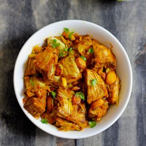 serial shot of kathal ki sabzi in a white ceramic bowl