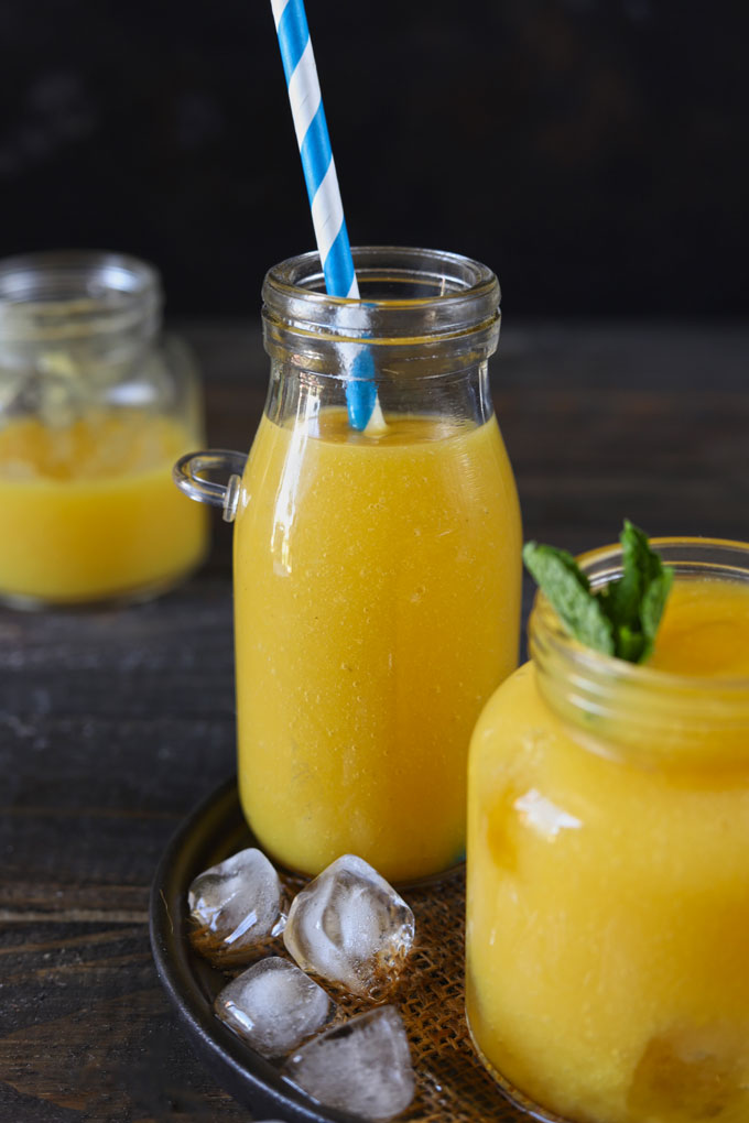Side shot of iced tea with mango flavor in a glass bottle.