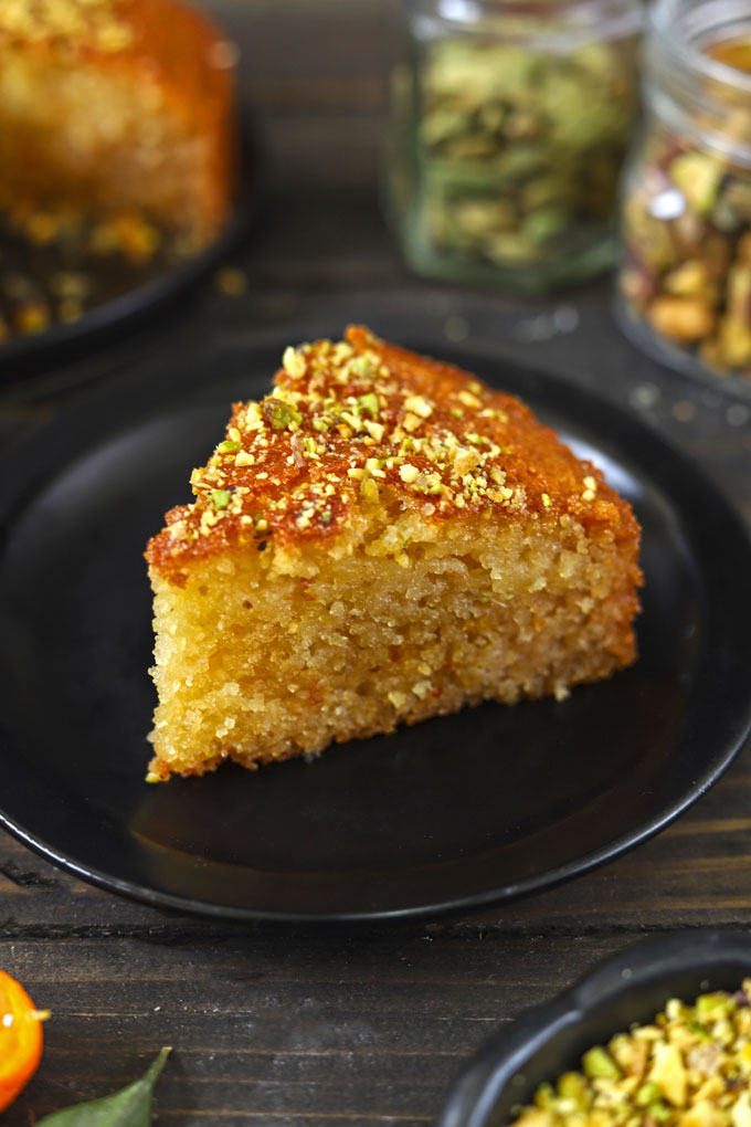 Side of rava cake slice on a black plate