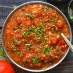 aerial shot of roasted tomato chutney in a steel bowl with a spoon