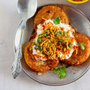 aerial shot of aloo tikki chaat in a steel plate with a spoon