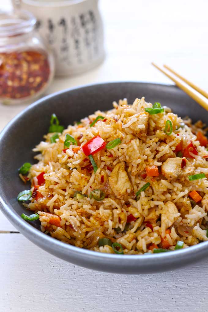 side shot of fried rice with chicken in a black ceramic bowl